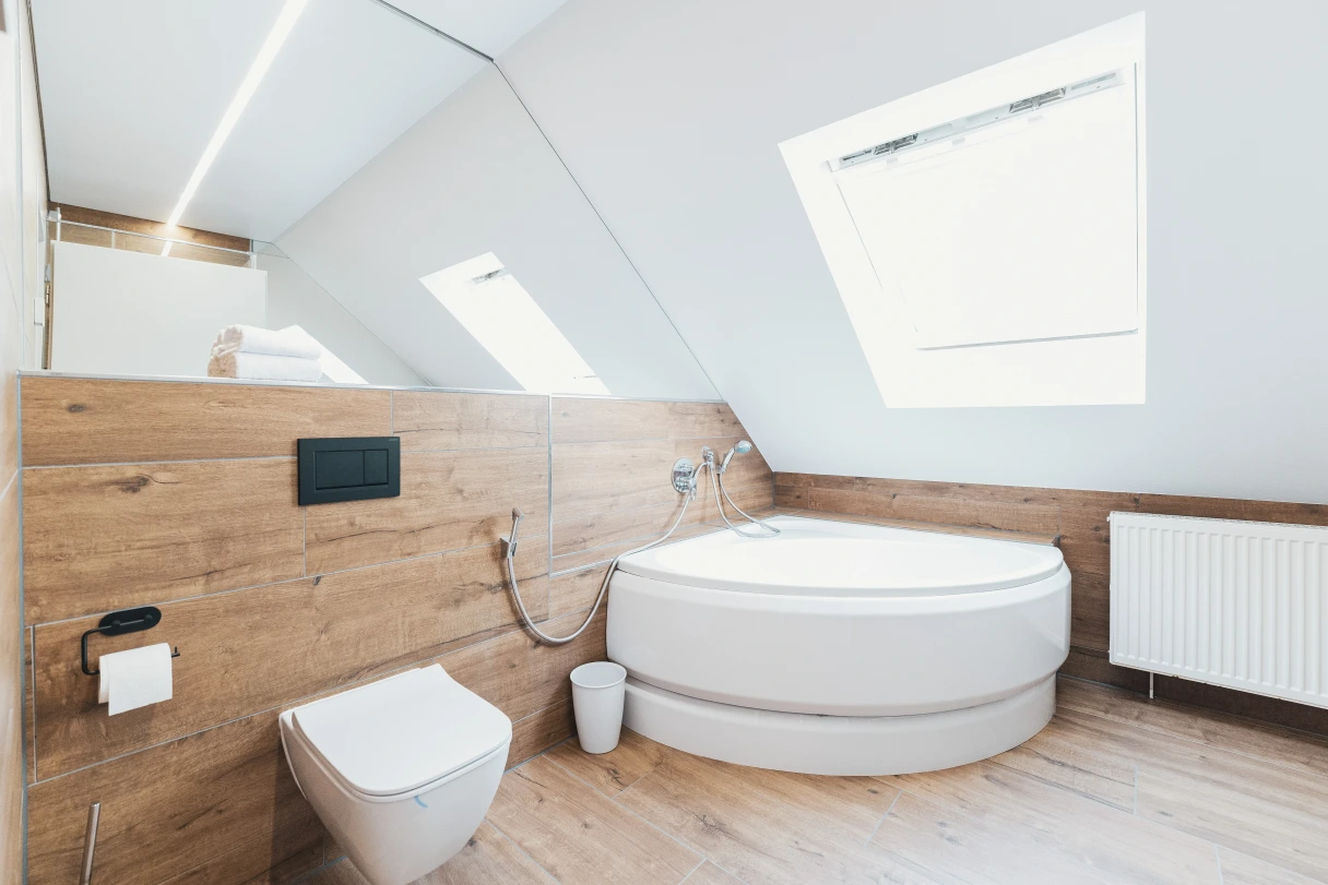 Bad mit Holzboden, Dachschräge, Toilette und Badewanne.