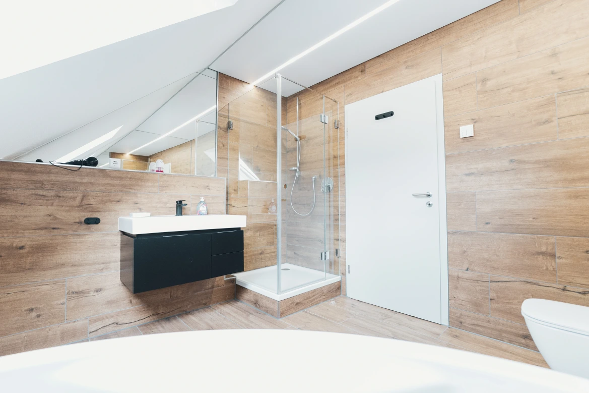 Bild der Dusche und Waschbecken des Badezimmers mit dem Holz-Optik-Boden.