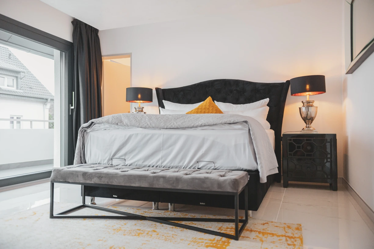 Erneut ein Bild vom schwarzem Bett mit dem orangenen Kissen.